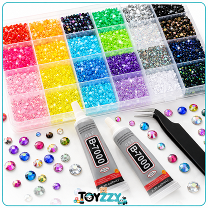 A crystal rhinestone beading kit on a white background, featuring a clear plastic organizer filled with colorful faceted beads, two tubes of Toyzz B-7000 adhesive, black tweezers, and scattered loose rhinestones.